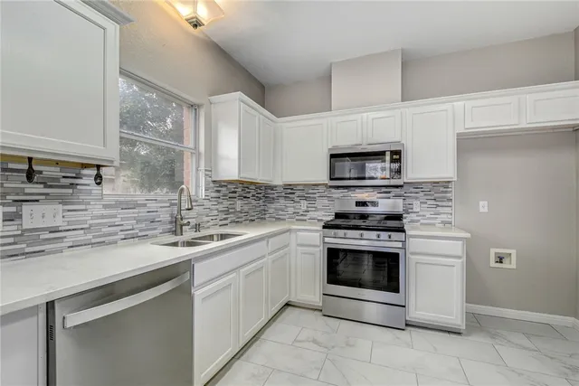a kitchen with stainless steel appliances granite countertop a sink stove and microwave