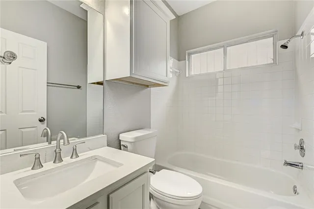 a bathroom with a bathtub shower sink vanity mirror and toilet