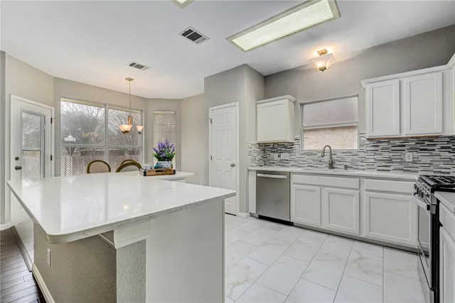 a kitchen with kitchen island granite countertop a sink stove and cabinets
