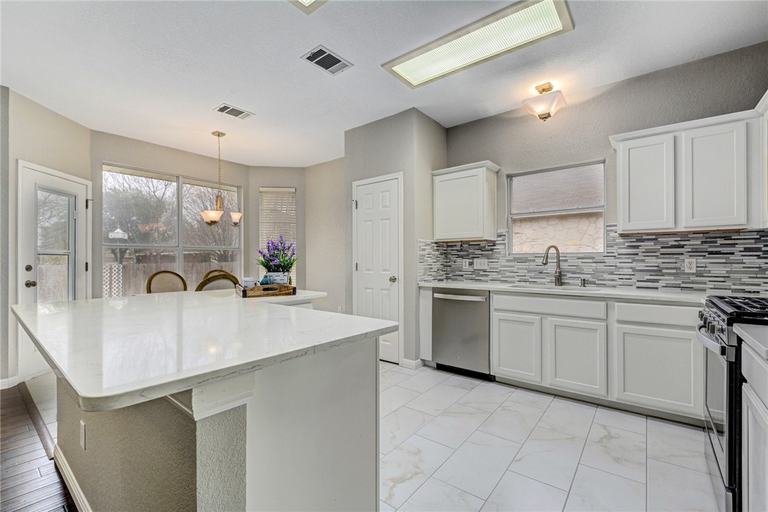 3504 Texas Topaz Drive Austin, TX 78728 - Photo 10 of 29 a kitchen with kitchen island granite countertop a sink stove and cabinets
