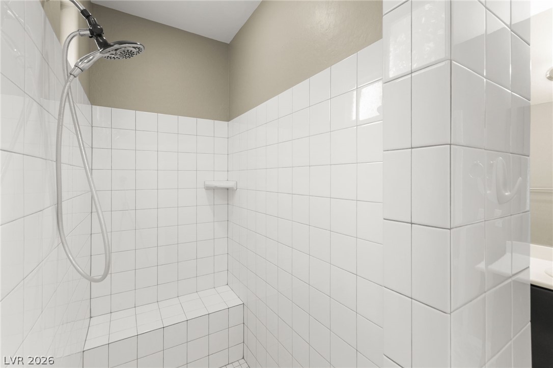 11048 Prairie Grove Road Las Vegas, NV 89179 - Photo 28 of 75 A well-appointed shower space offers clean white tiling and an integrated bench for comfort.