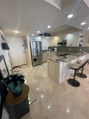 a kitchen with stainless steel appliances kitchen island granite countertop a sink and a stove
