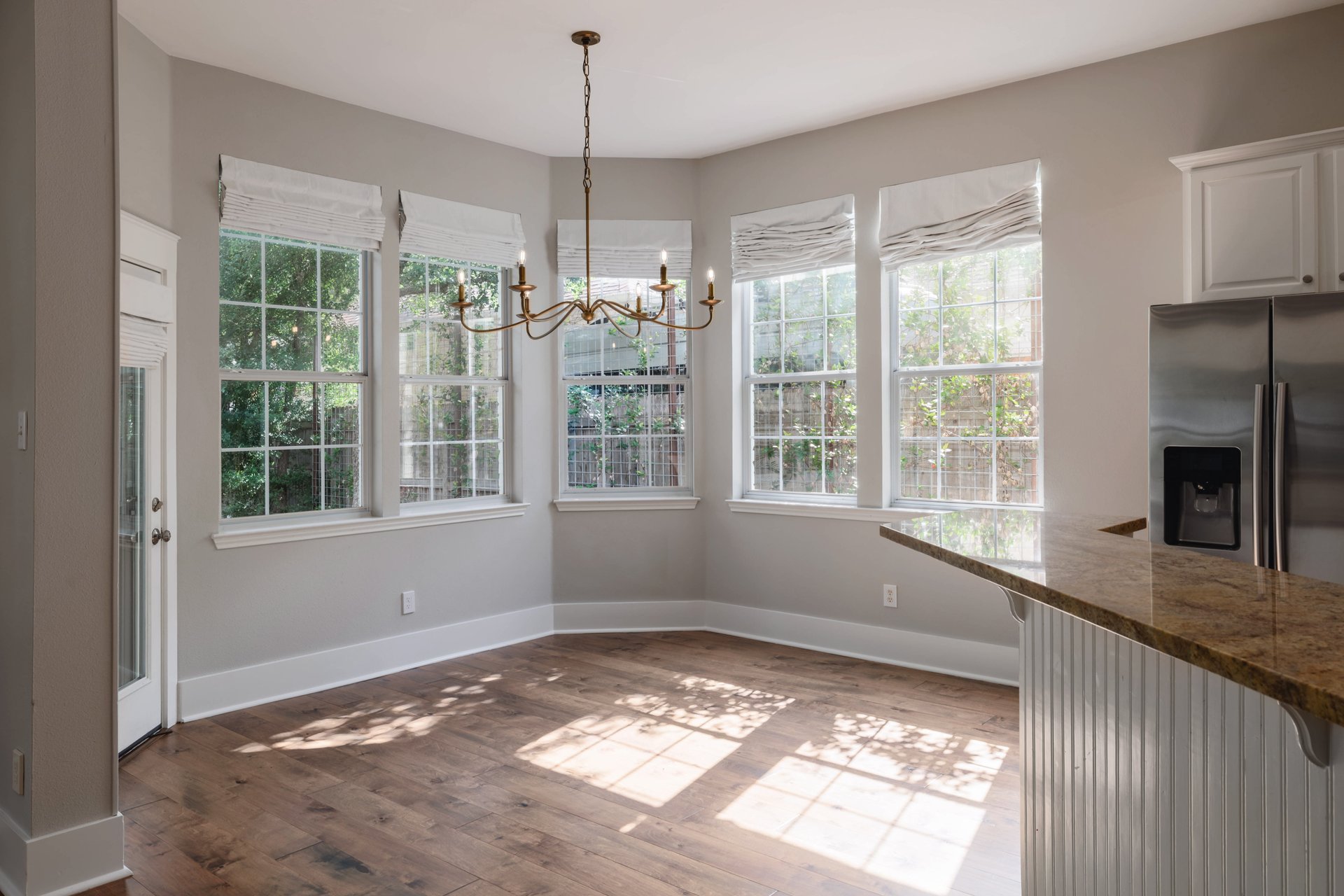 5512 Ballenton Lane Austin, TX 78739 - Photo 17 of 40 Natural light floods this inviting dining area, highlighting the beautiful hardwood flooring and elegant chandelier.