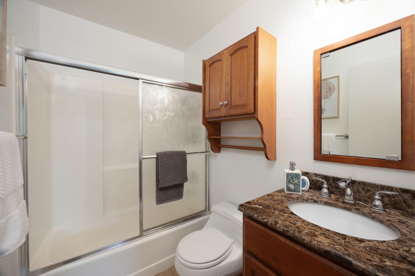 1204 Rainier Avenue Pacifica, CA 94044 - Photo 24 of 38 a bathroom with a granite countertop sink toilet a mirror a vanity and shower