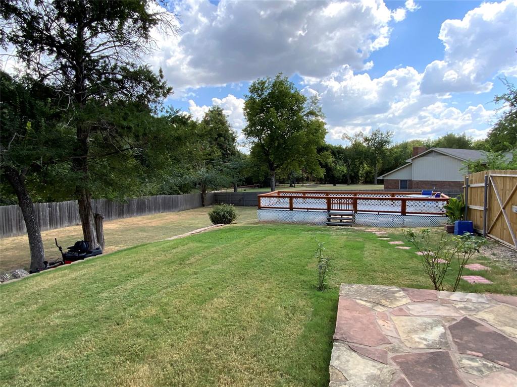 2020 Arbor Bend Road Bonham, TX 75418 - Photo 29 of 30 Expansive backyard featuring a manicured lawn, established trees, private wood fencing, stone patio, and a swimming pool with a surrounding deck