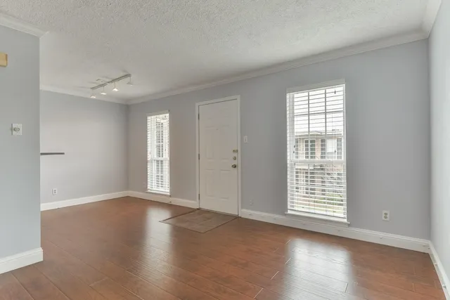 an empty room with wooden floor and windows