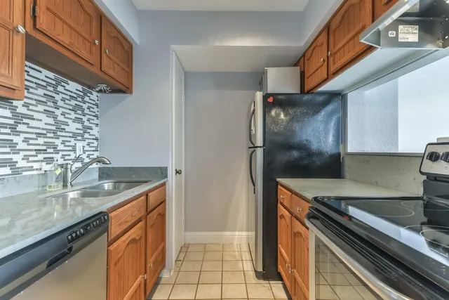 a kitchen with granite countertop a sink stove and refrigerator