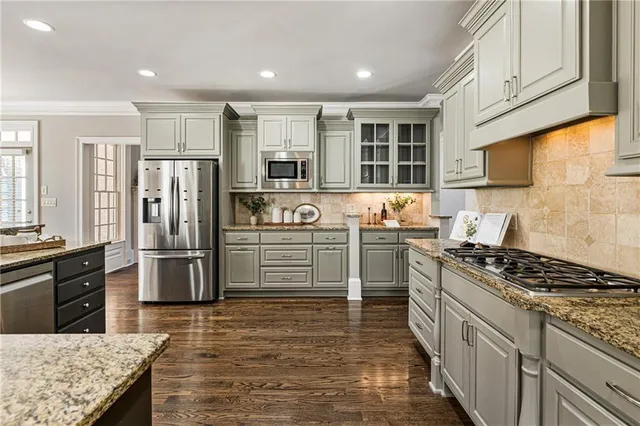 a kitchen with stainless steel appliances granite countertop a kitchen island hardwood floor and a sink