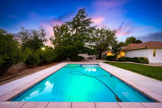 a view of a big house with a big yard plants and large trees