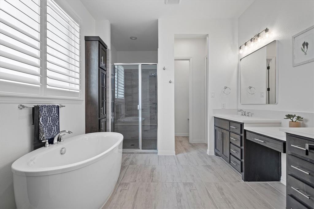 1561 William Way Dallas, TX 75234 - Photo 12 of 38 a bathroom with a bathtub a double vanity sink a window and a mirror