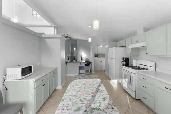 a large white kitchen with stainless steel appliances granite countertop a sink and cabinets