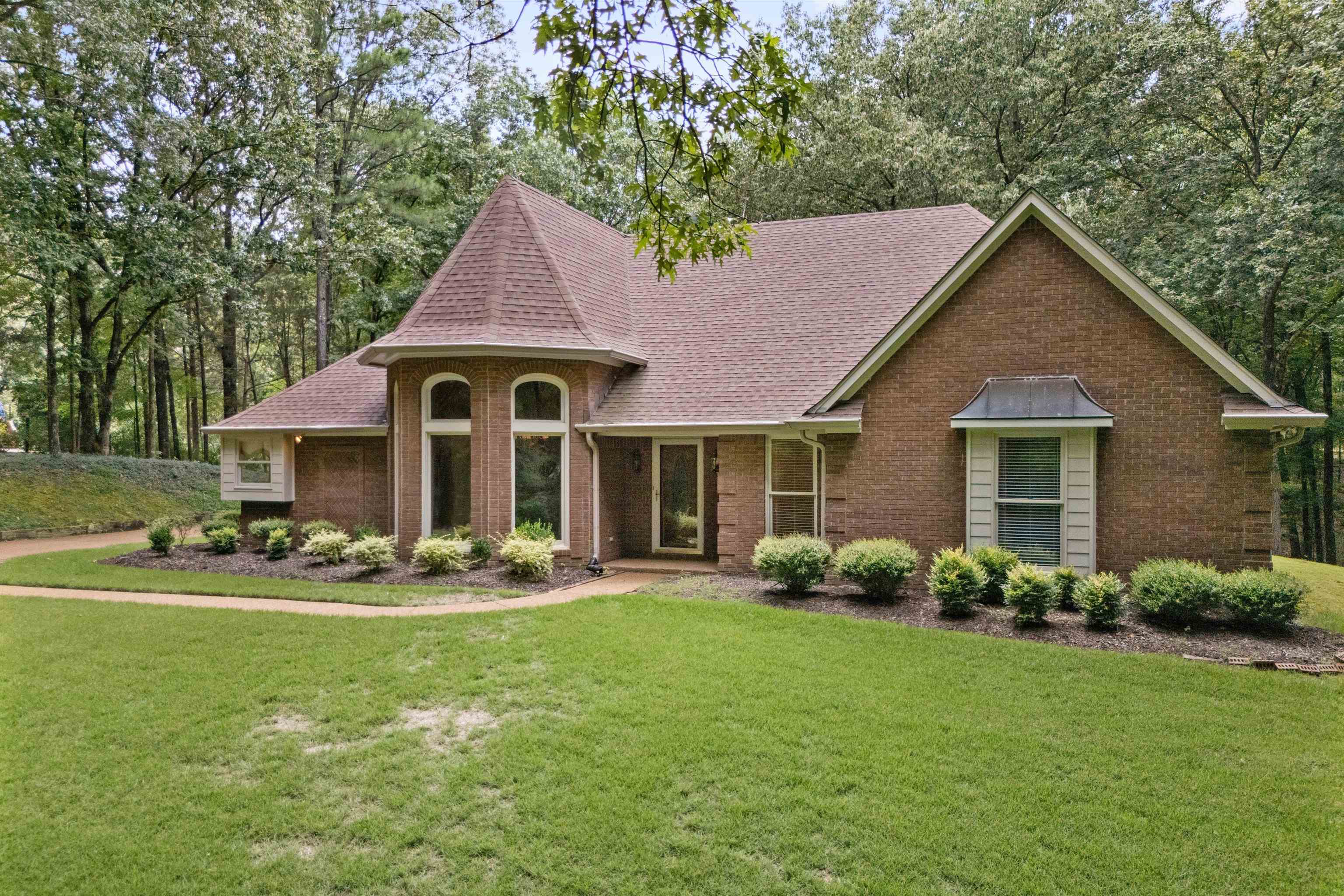 View of front facade with roof with shingles, a front yard, and brick siding