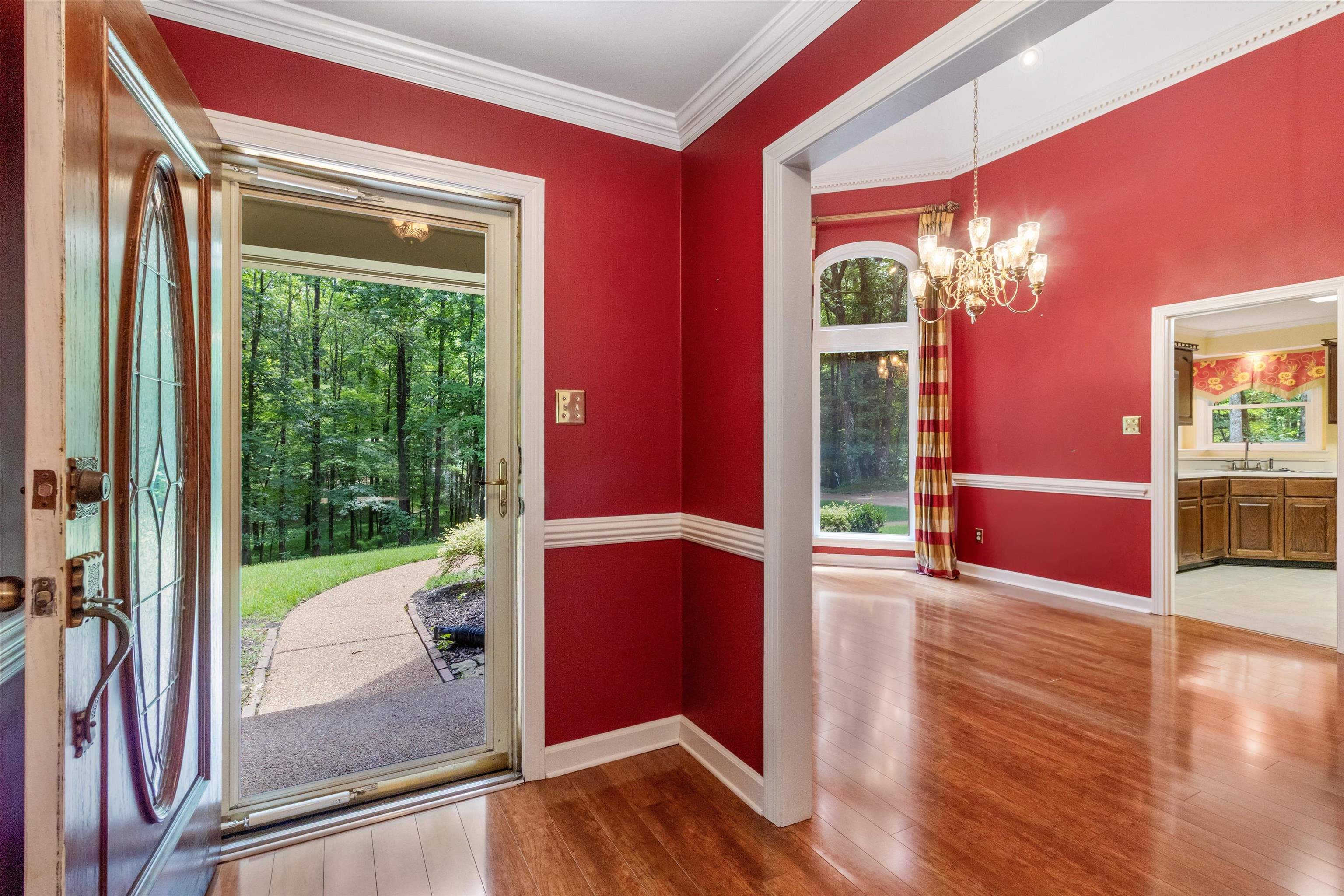 Entryway with wood finished floors, a chandelier, healthy amount of natural light, and ornamental molding