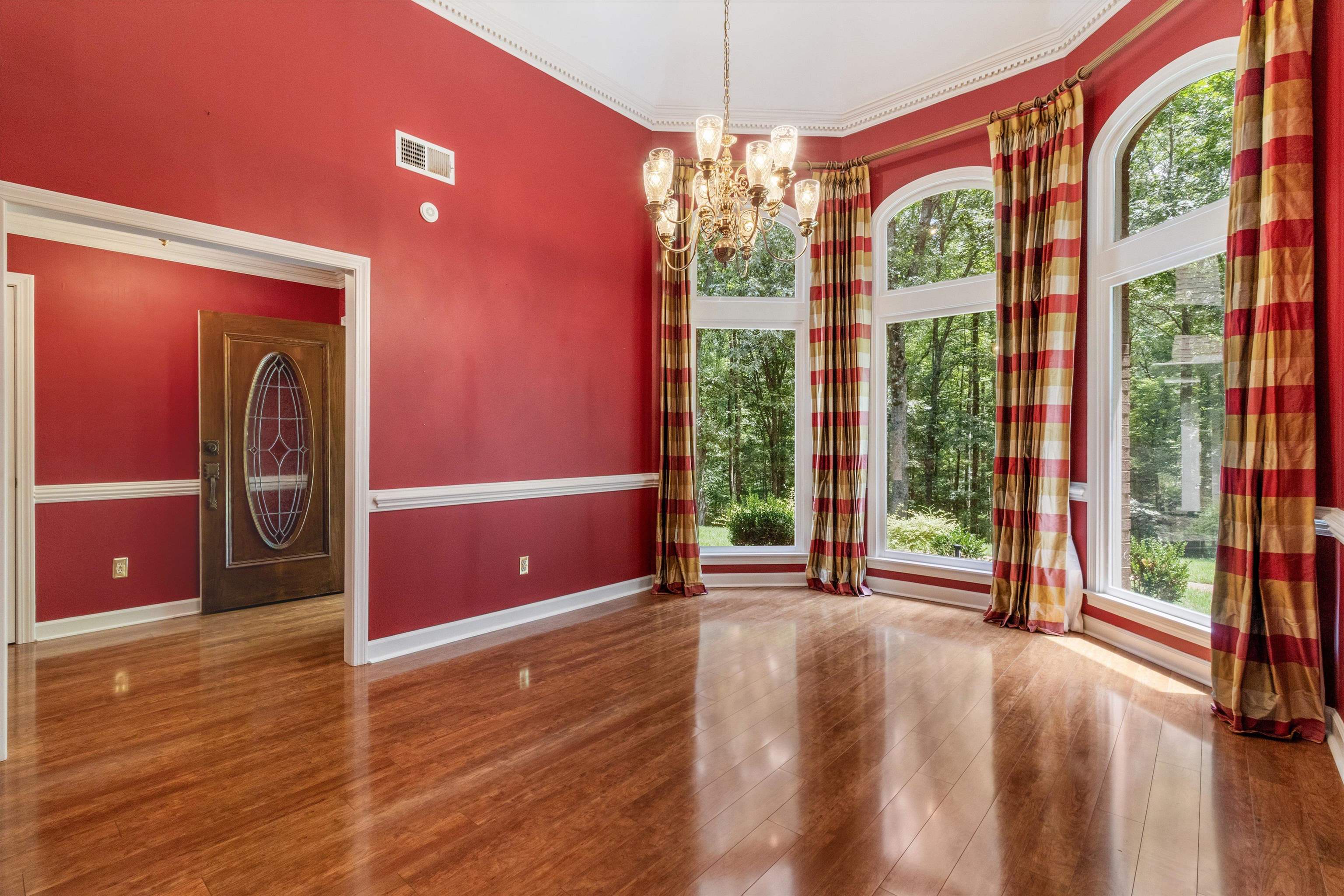 Empty room featuring a chandelier, wood finished floors, ornamental molding, and a towering ceiling