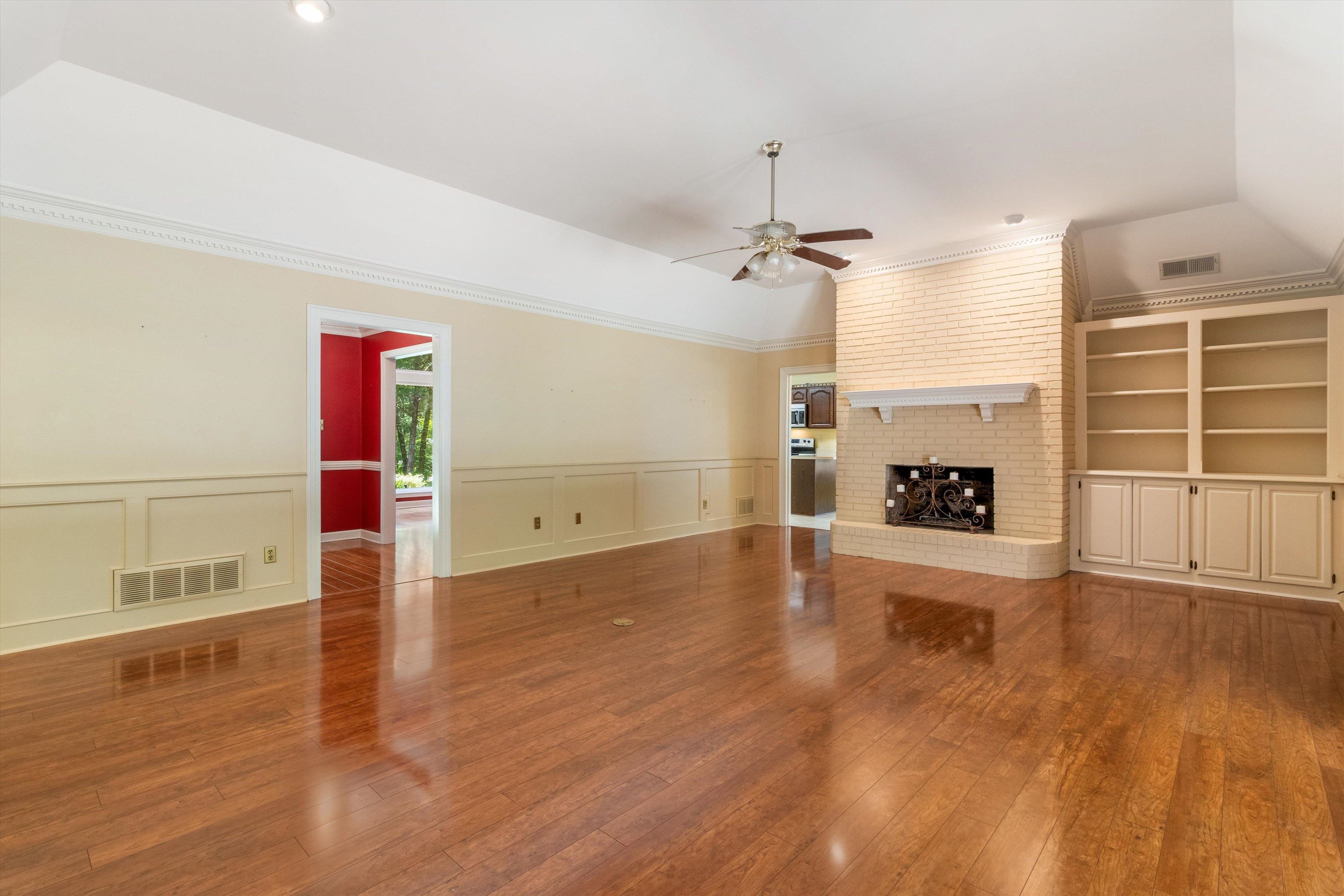 4081 Brunswick Road Bartlett, TN 38133 - Photo 9 of 31 Unfurnished living room with a ceiling fan, a decorative wall, wood-type flooring, a fireplace, and a wainscoted wall