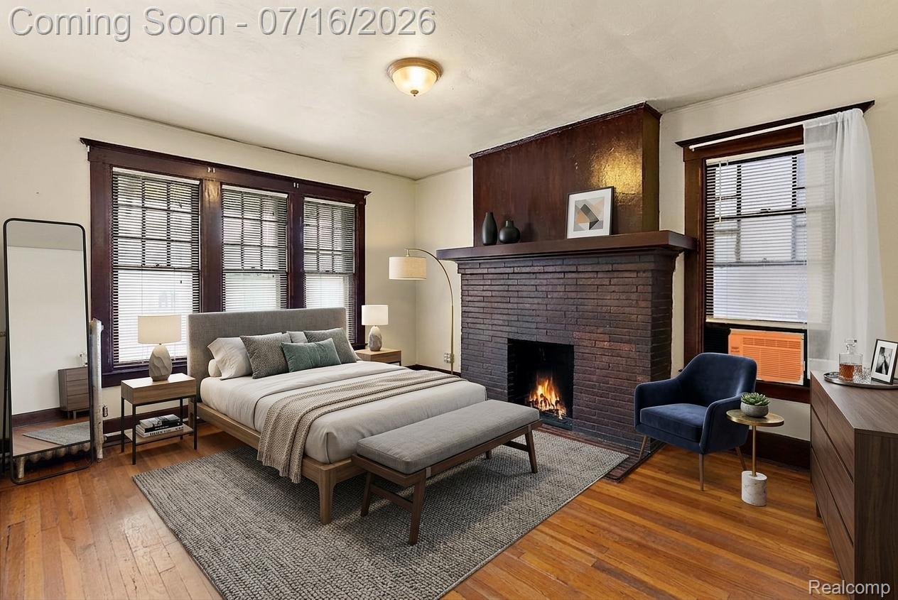 4157 Trumbull Detroit, MI 48208 - Photo 4 of 47 Spacious room featuring hardwood flooring, a brick fireplace with a wood mantle, three windows with dark wood trim, and a built-in ceiling light fixture