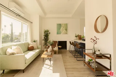 a living room with furniture and a large mirror next to a window