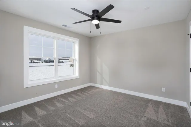 an empty room with windows and ceiling fan