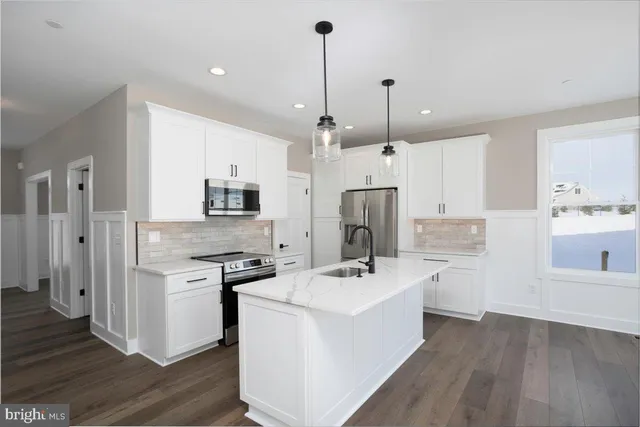 a kitchen with a sink stainless steel appliances and wooden floor
