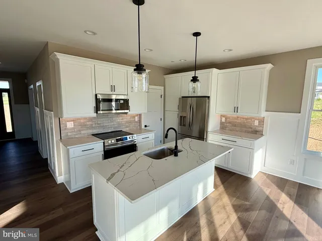 a kitchen with stainless steel appliances granite countertop a stove a sink a refrigerator a center island a stove and a wooden floor