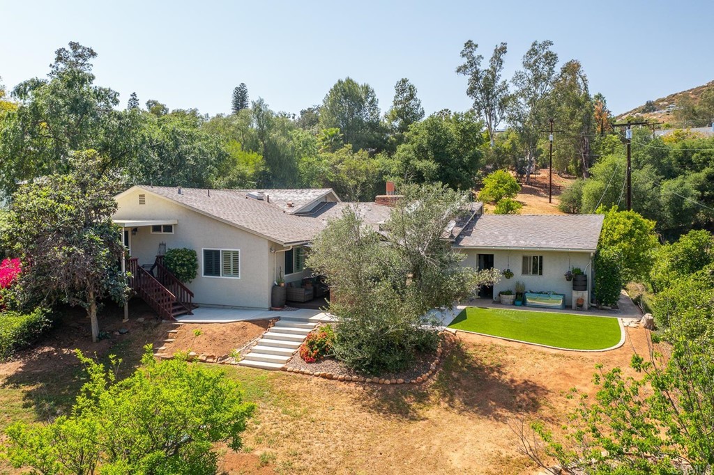 11493 Eucalyptus Hills Drive Lakeside, CA 92040 - Photo 3 of 30 a view of a white house with a swimming pool and lawn chairs with plants