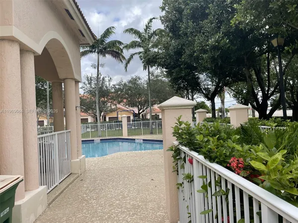 a view of a house with a small yard and large trees