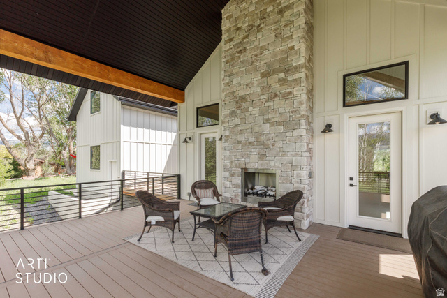 1188 South Old Trappers Loop Road Huntsville, UT 84317 - Photo 64 of 92 Covered outdoor living area featuring a stone fireplace, durable composite decking, board and batten siding, substantial exposed wood beam, and black metal railings