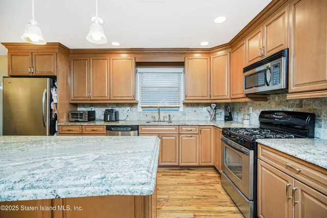 a kitchen with stainless steel appliances granite countertop a stove a sink dishwasher and a refrigerator