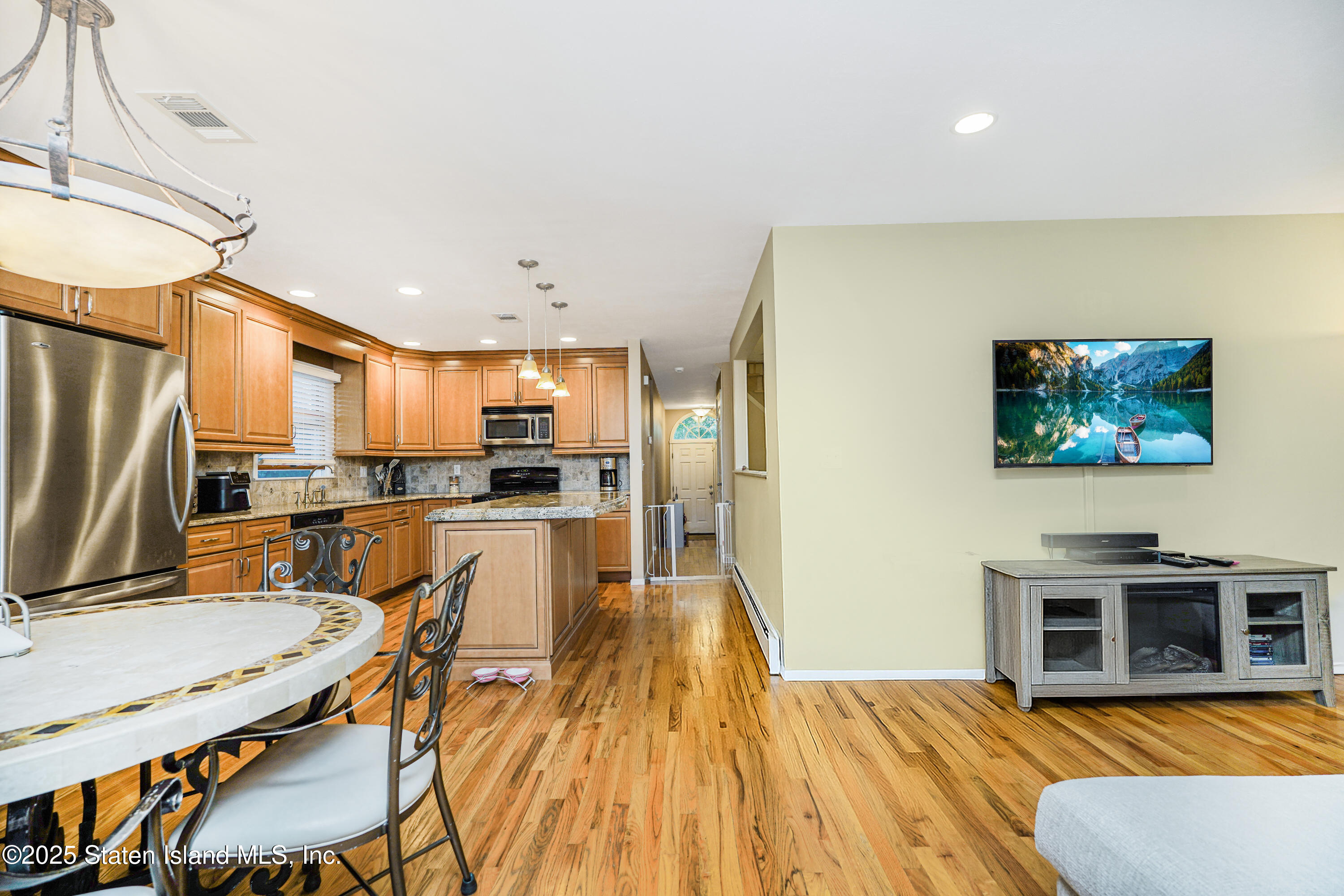 145 Shirley Avenue Staten Island, NY 10312 - Photo 9 of 29 a kitchen with stainless steel appliances granite countertop a refrigerator a stove a sink a dining table and chairs with wooden floor