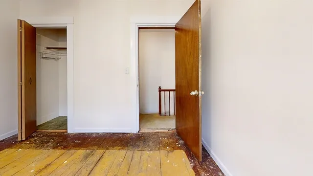 a view of a hallway with wooden floor and a bathroom