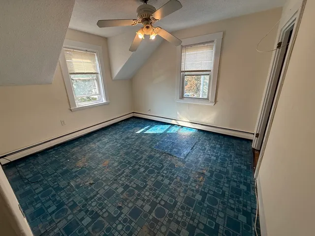 an empty room with windows and fan