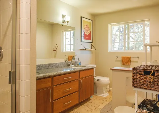 a bathroom with a granite countertop toilet sink and mirror