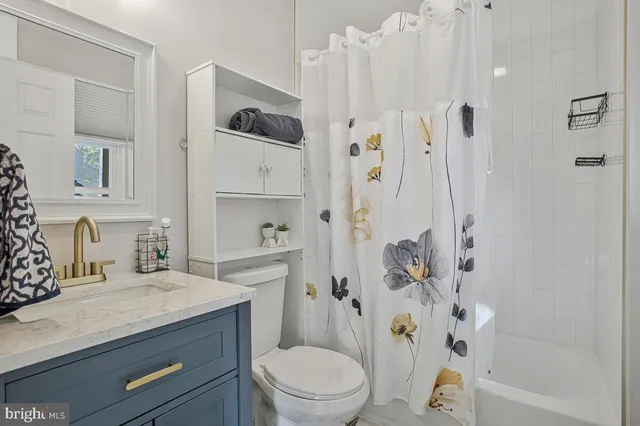 a bathroom with a granite countertop sink a toilet and shower