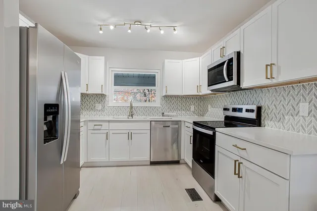 a kitchen with stainless steel appliances granite countertop a refrigerator sink stove microwave and cabinets