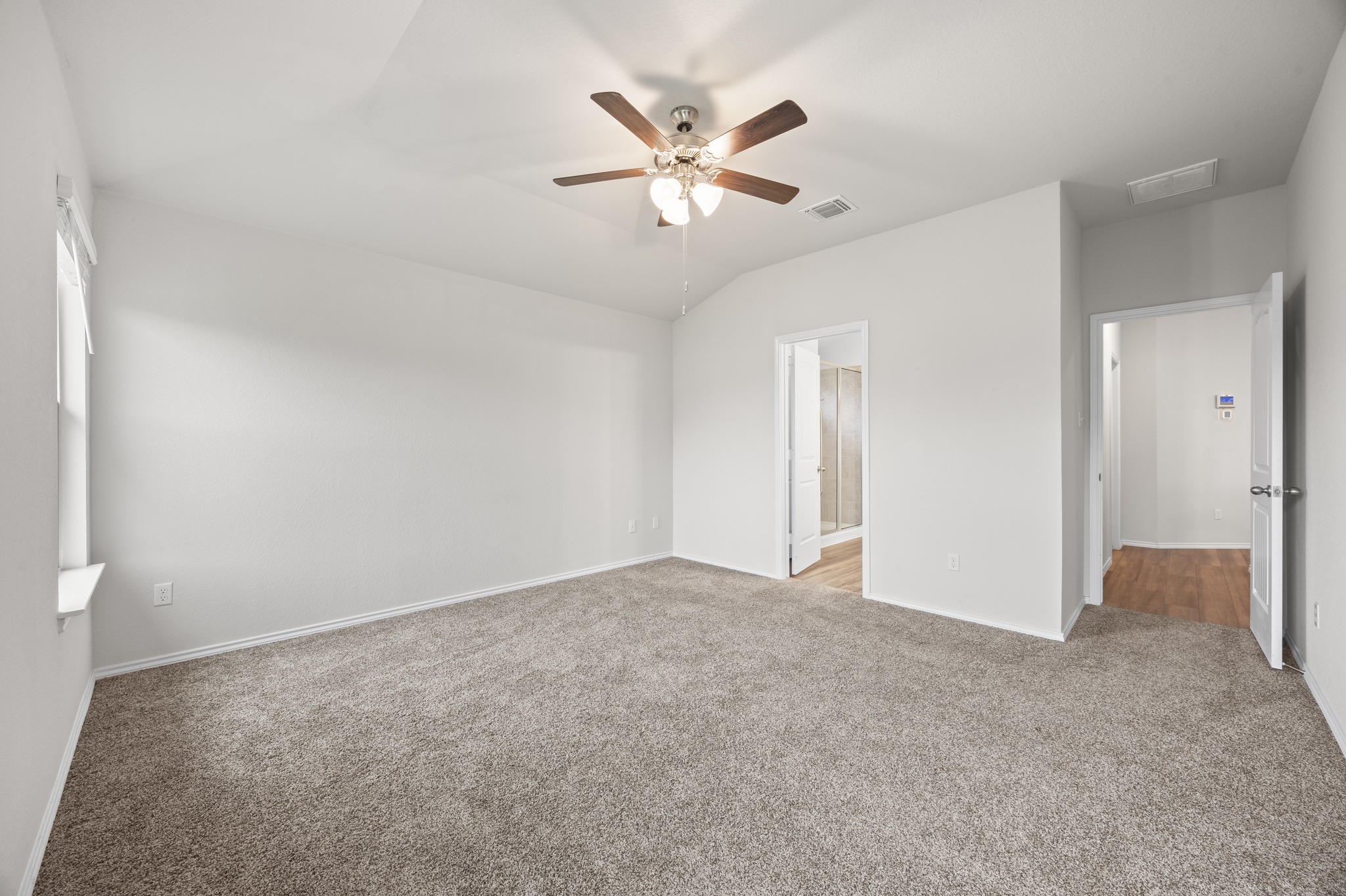 109 Gunther Way Taylor, TX 76574 - Photo 13 of 29 Spacious room featuring vaulted ceilings, light-tone carpeting, a ceiling fan with integrated lighting, and multiple doorways providing access to other areas of the property