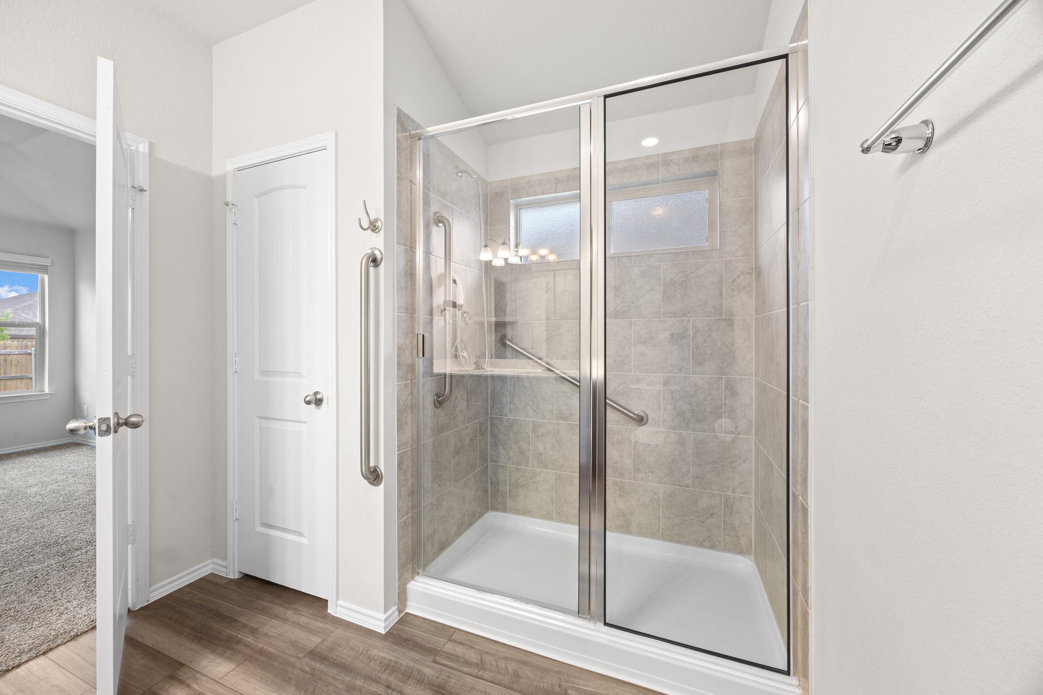 109 Gunther Way Taylor, TX 76574 - Photo 17 of 29 Glass-enclosed shower featuring light-toned tile surround, integrated shelving, and dual grab bars