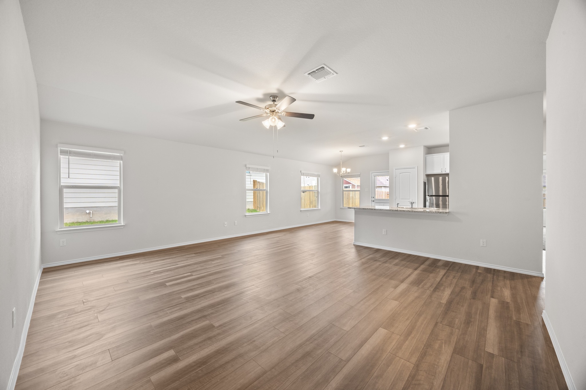 109 Gunther Way Taylor, TX 76574 - Photo 4 of 29 Expansive open-concept living area featuring wood-look LVP flooring, multiple windows, and a ceiling fan