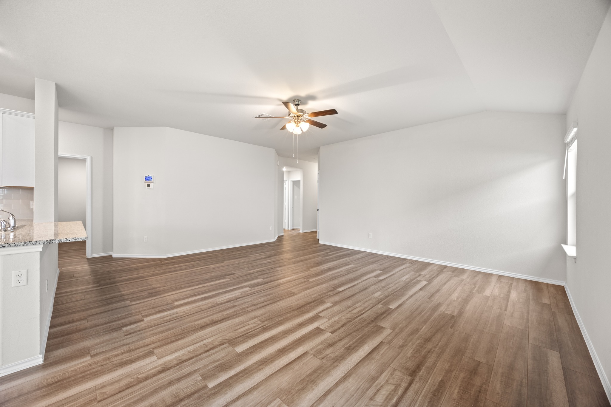 109 Gunther Way Taylor, TX 76574 - Photo 5 of 29 Spacious room featuring wood-look LVP flooring, vaulted ceilings, and a ceiling fan with light fixture