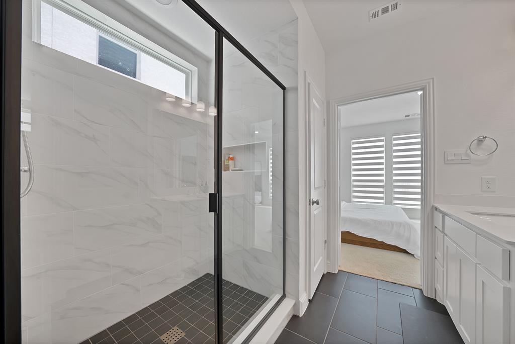 5012 Triadic Lane Prosper, TX 75078 - Photo 21 of 38 Spacious walk-in shower with black-framed glass enclosure, white marble-look tile surround, and dark tile flooring