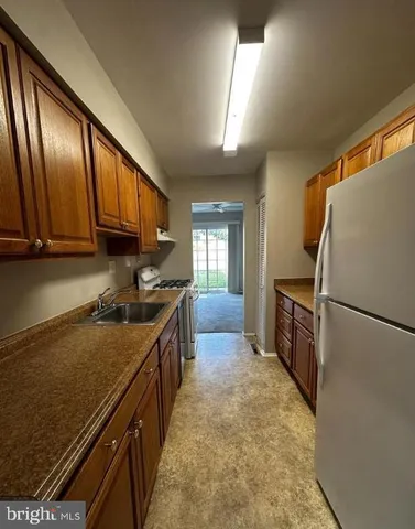 a kitchen with granite countertop a refrigerator stove and sink