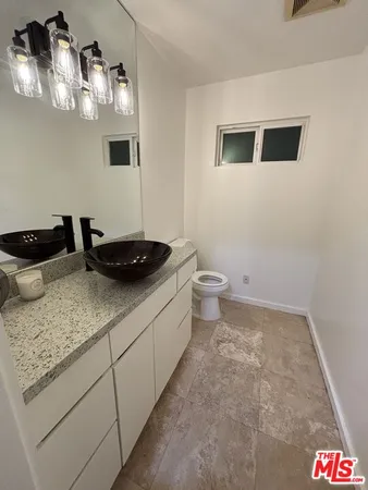 a bathroom with a granite countertop sink and a toilet
