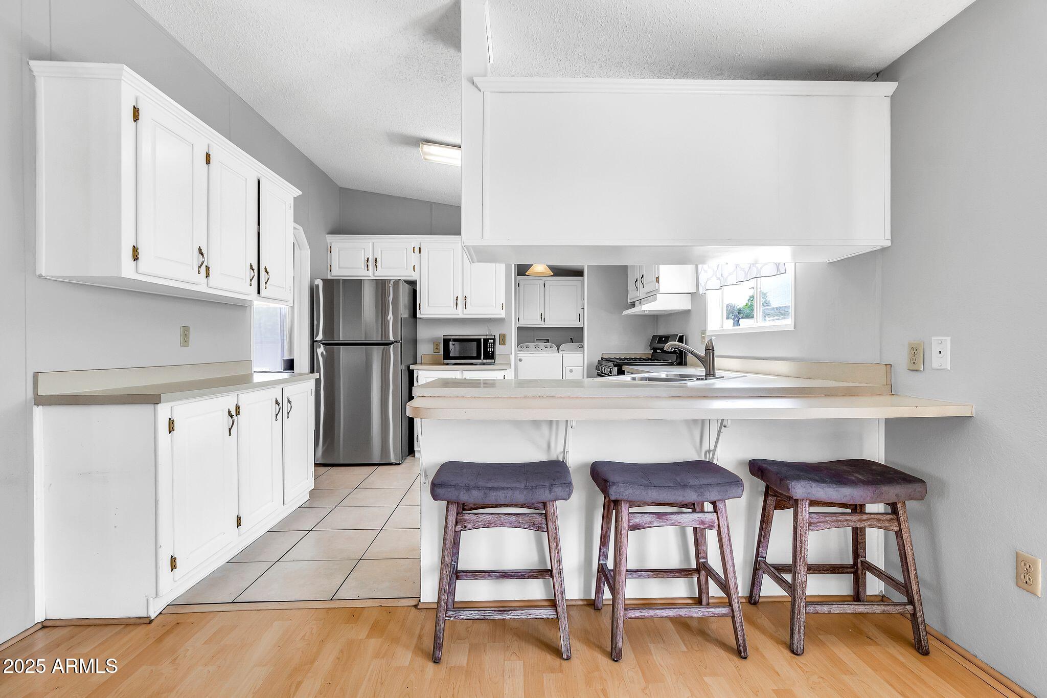 625 West McKellips Road, Unit 399 Mesa, AZ 85201 - Photo 7 of 31 a kitchen with white cabinets and chairs