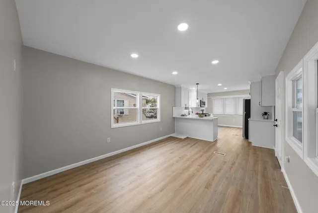 a kitchen with stainless steel appliances a sink a refrigerator white cabinets and wooden floor