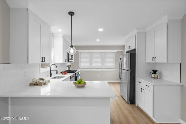 a kitchen with stainless steel appliances granite countertop a stove top oven a sink dishwasher and a refrigerator with wooden floor