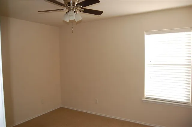 an empty room with a window and a fan