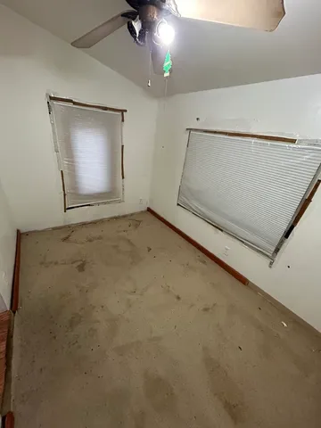 an empty room with a ceiling fan and carpet