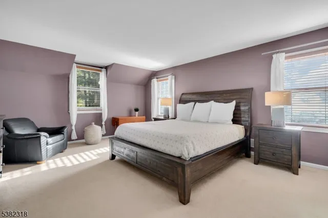 a bedroom with a bed couch and windows