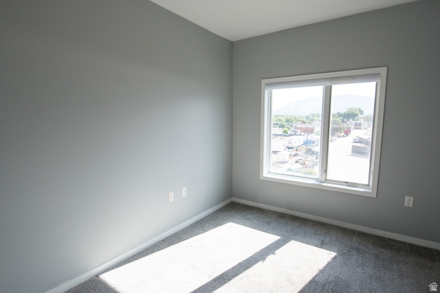 2150 South Main Street, Unit R405 Salt Lake City, UT 84115 - Photo 20 of 20 Spacious room featuring a large window, neutral gray wall paint, white trim, and soft carpeting