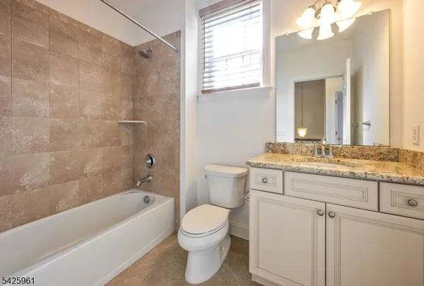 a bathroom with a granite countertop sink a toilet and bathtub