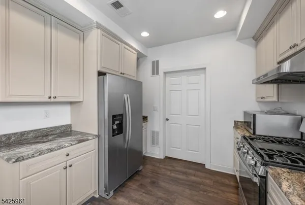 a kitchen with stainless steel appliances granite countertop a refrigerator and a stove top oven